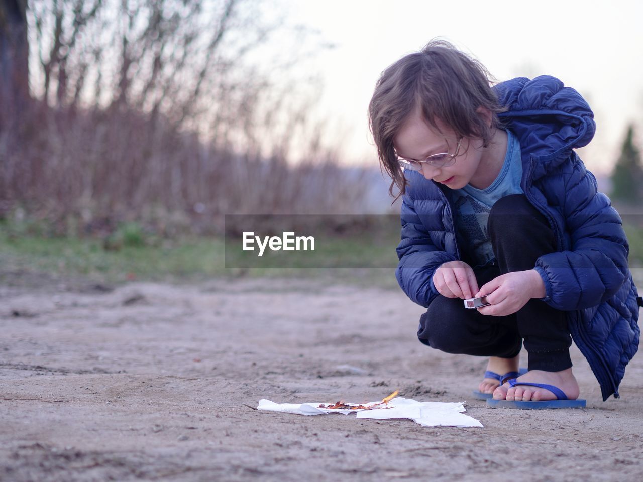 Full length of boy burning papers on land