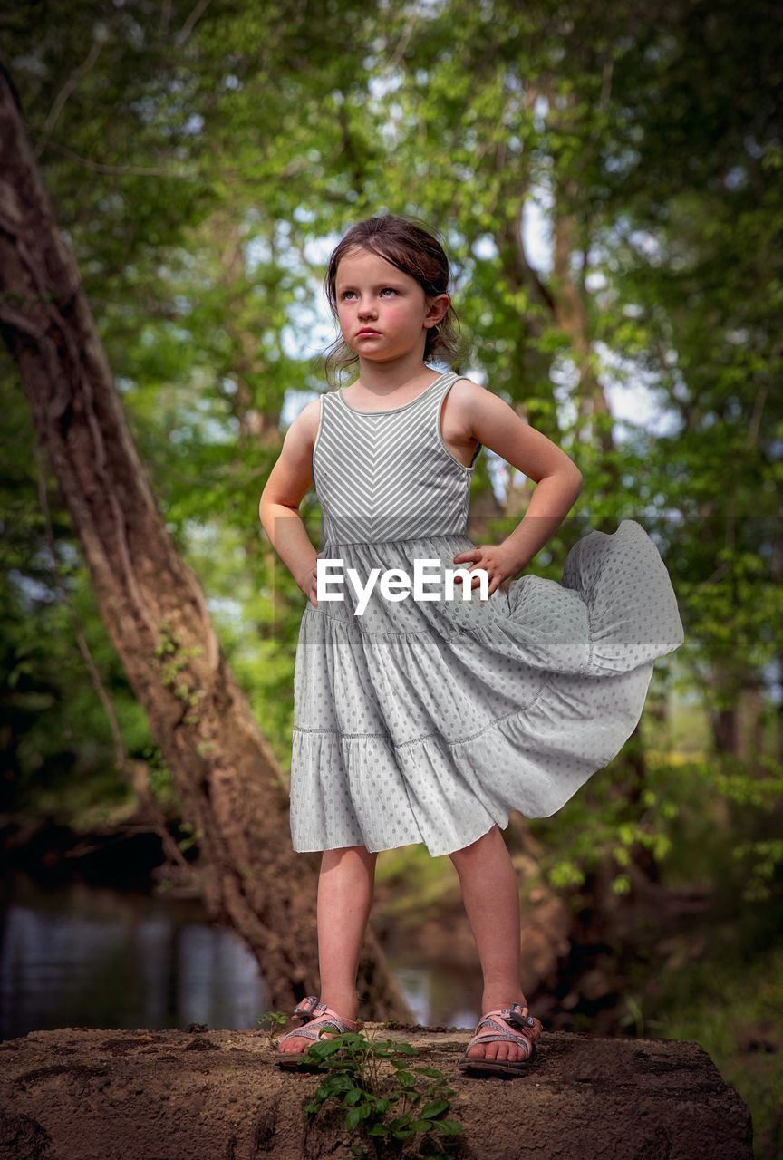 FULL LENGTH OF A GIRL STANDING AGAINST TREES