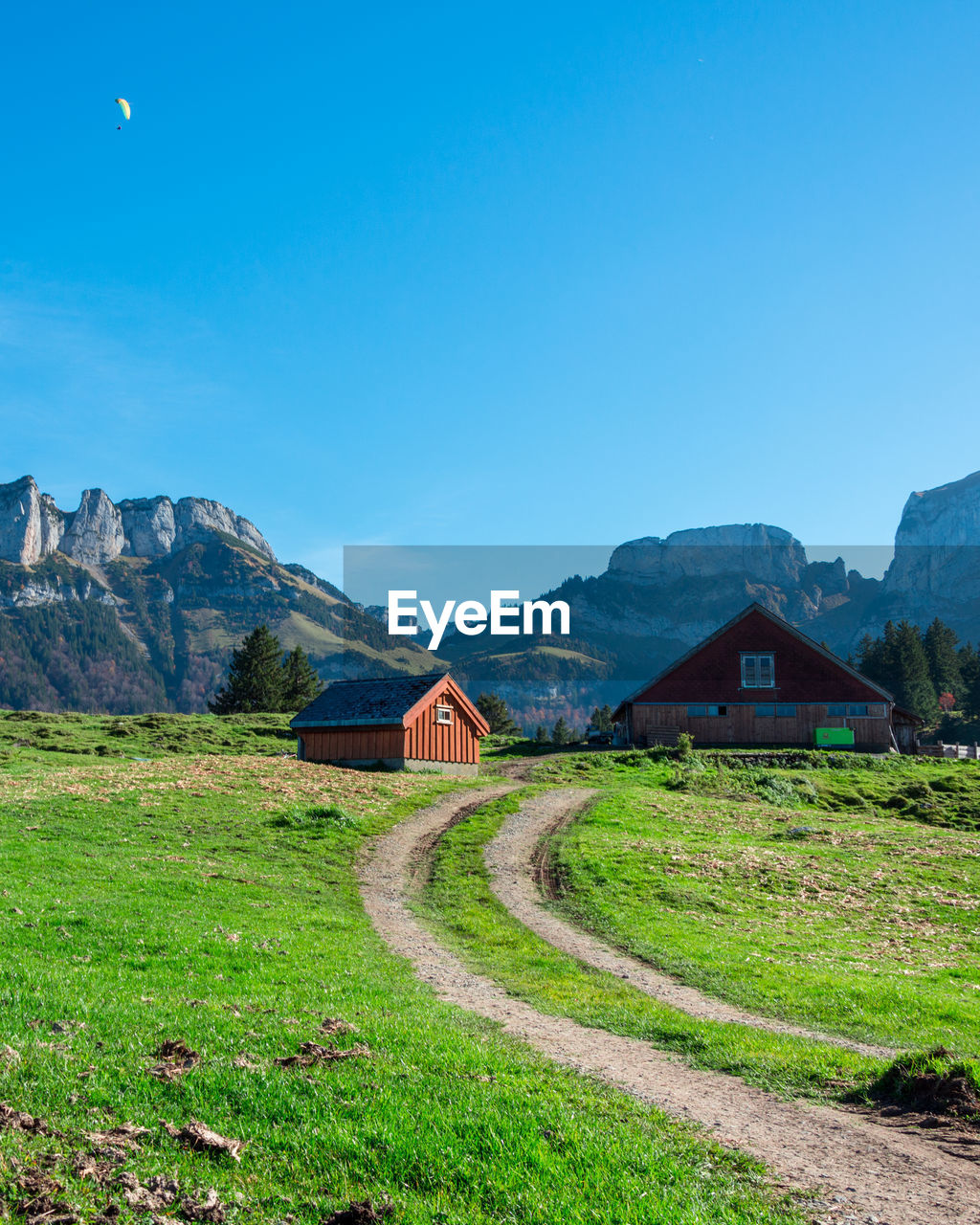 Houses on field by mountain against blue sky