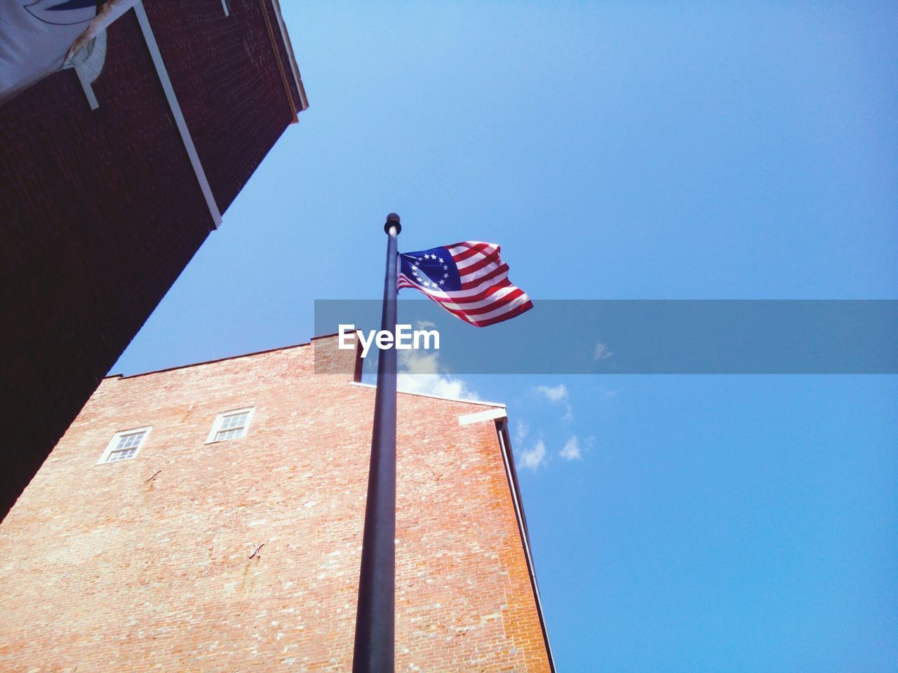 Low angle view of flag against clear blue sky