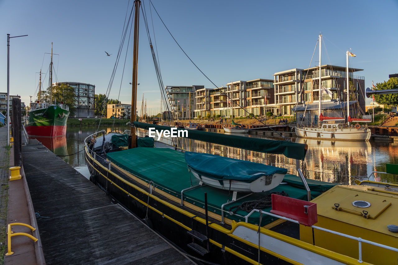 Boats moored at harbor against sky in city