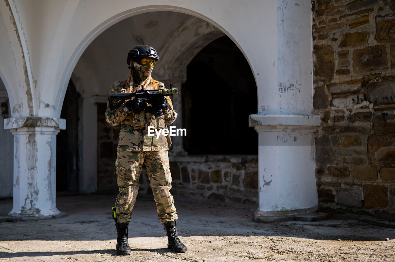 Army soldier with rifle against building