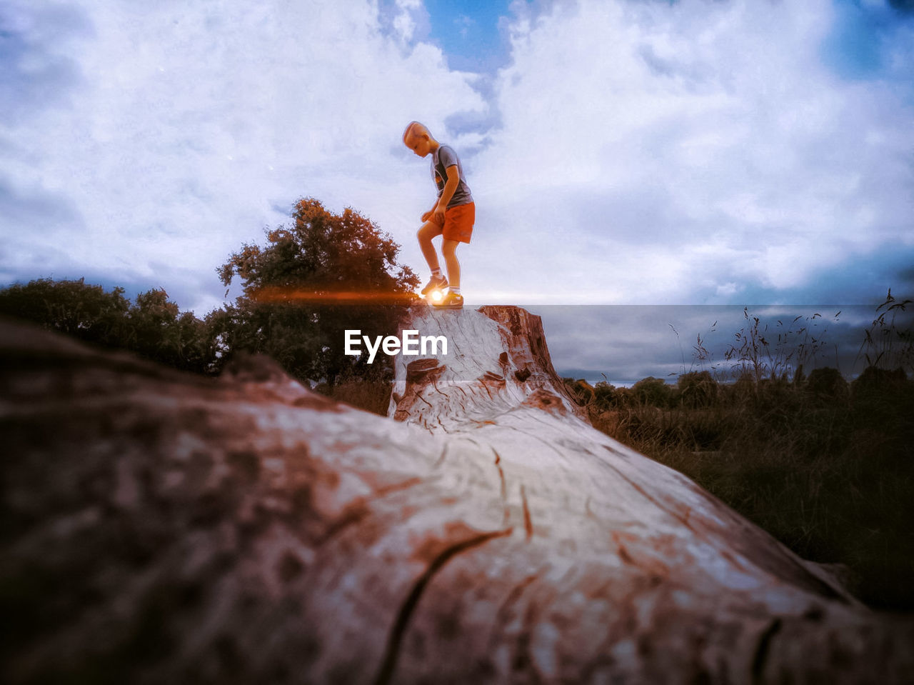 LOW ANGLE VIEW OF MAN STANDING ON ROCK