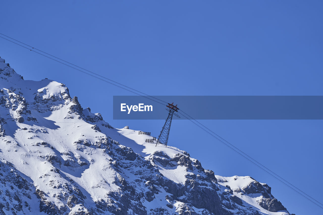 LOW ANGLE VIEW OF SNOWCAPPED MOUNTAIN AGAINST CLEAR BLUE SKY
