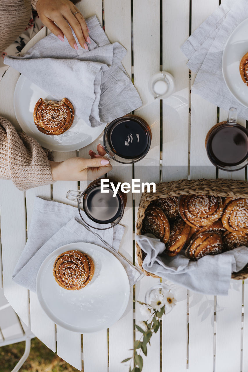 High angle view of coffee mugs and cinnamon buns on wooden table