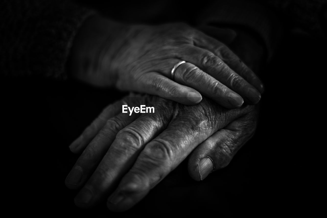Cropped hands of senior couple against black background