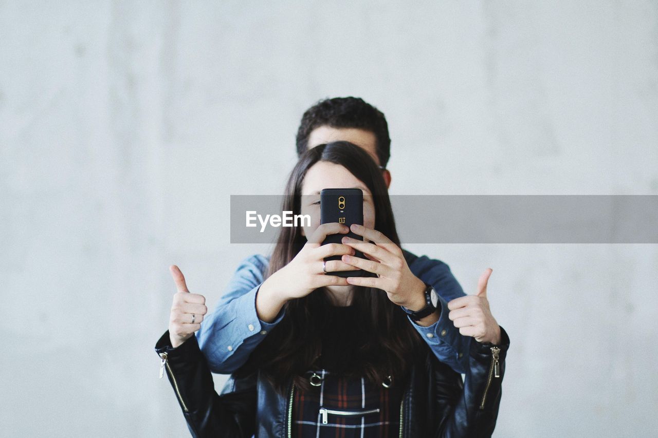 Couple taking selfie against wall