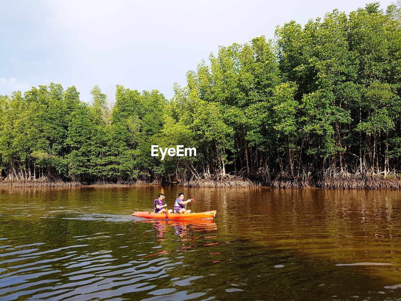 PEOPLE IN LAKE AGAINST SKY