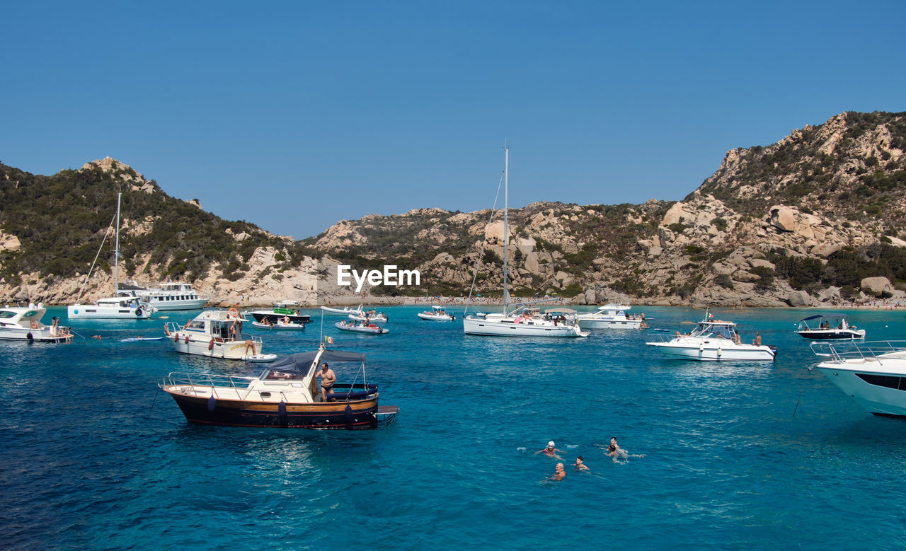 SAILBOATS MOORED ON SEA AGAINST CLEAR SKY