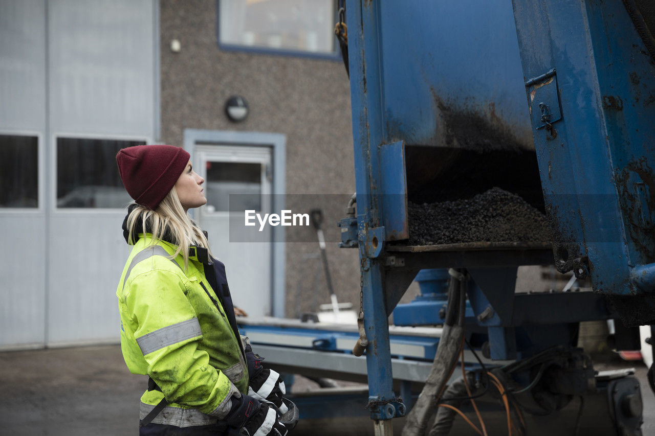Young female construction worker operating machinery