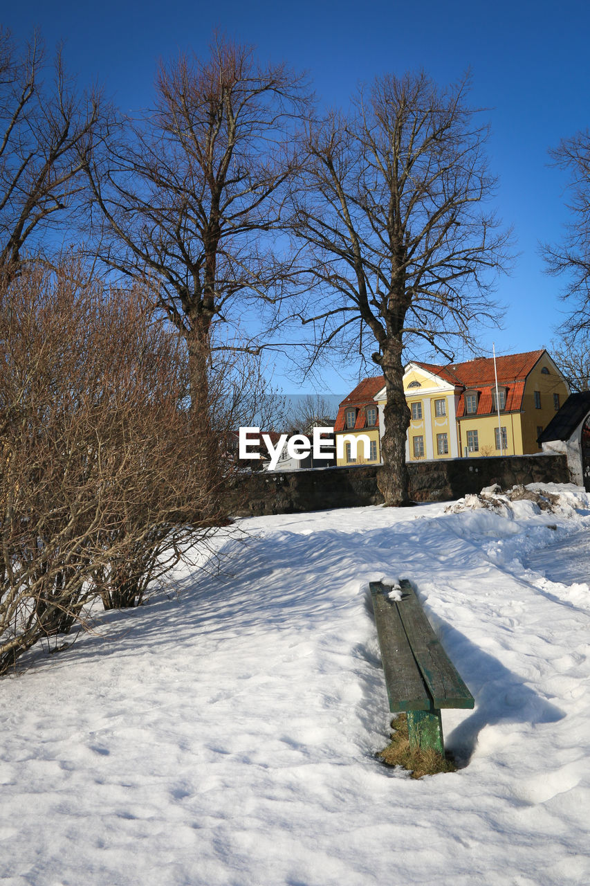 SNOW COVERED HOUSES ON FIELD AGAINST SKY