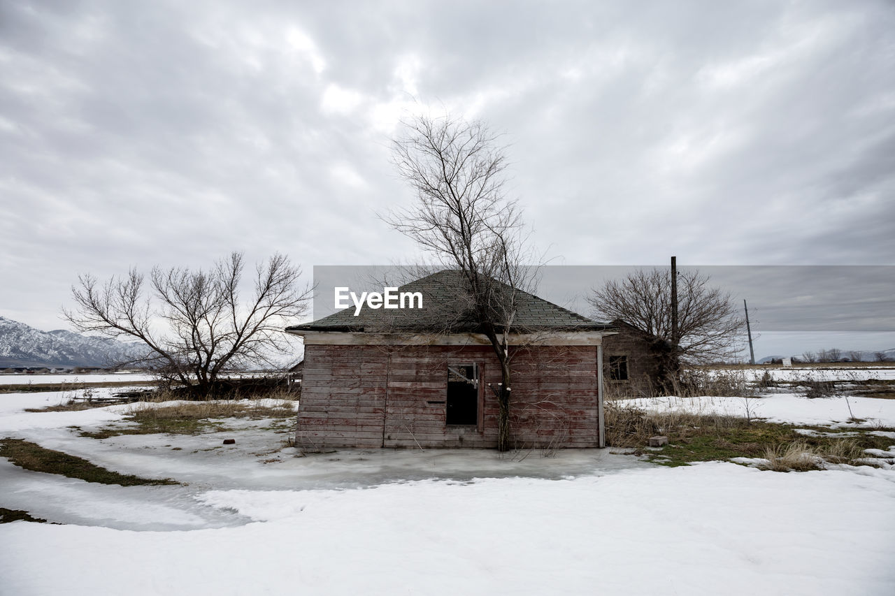 HOUSE BY BARE TREES AGAINST SKY