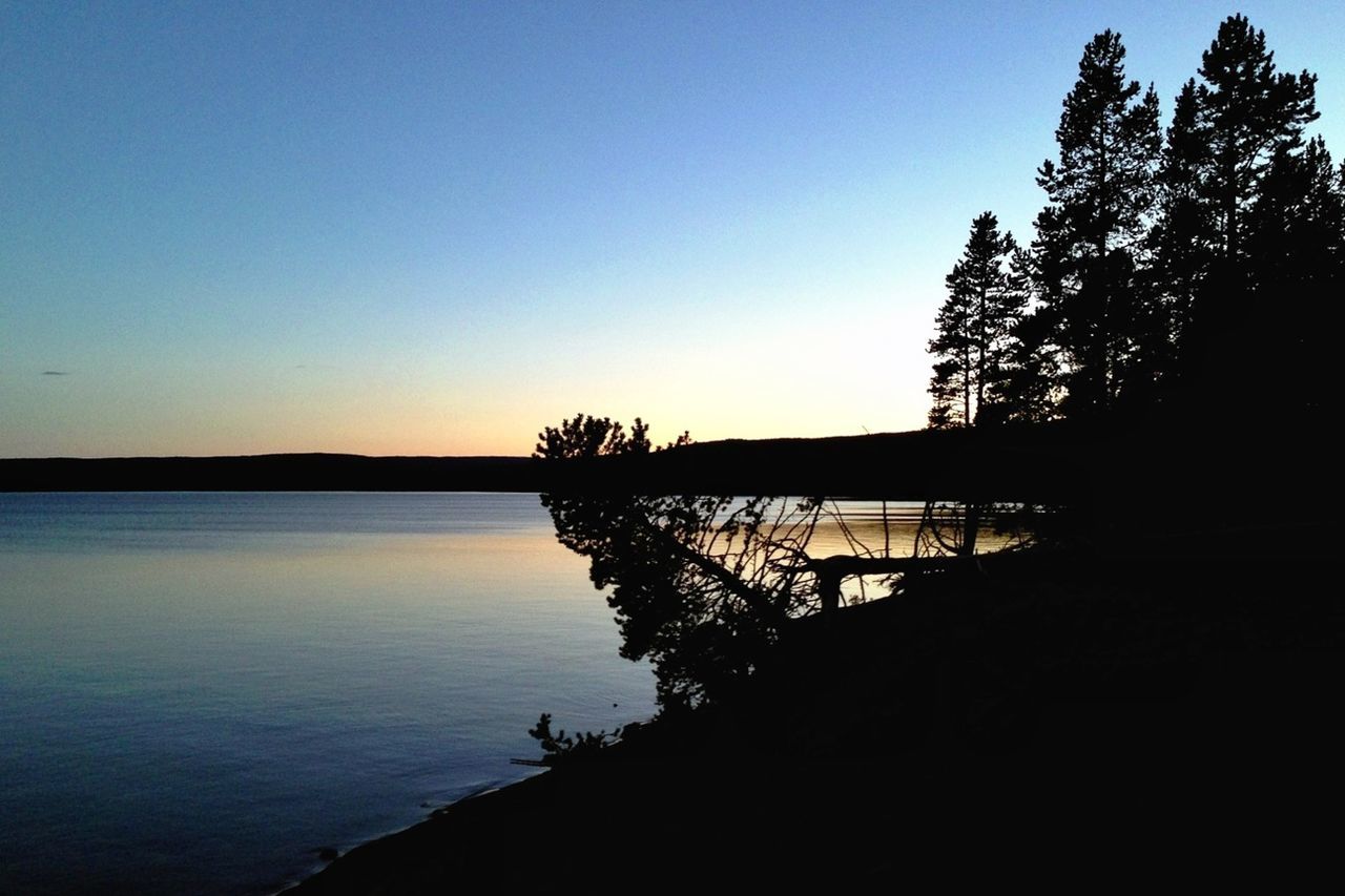 Calm countryside lake along silhouette trees