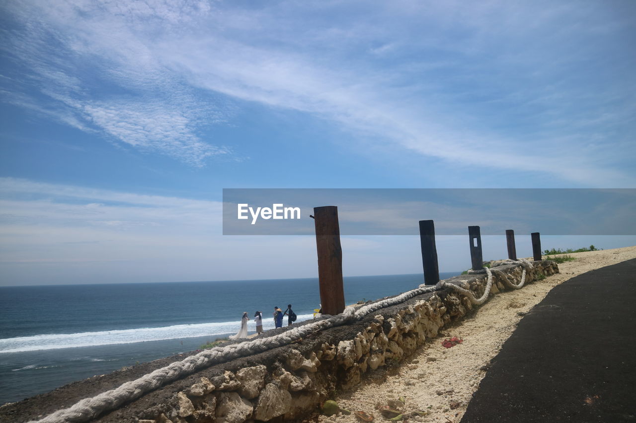 WOODEN POST ON BEACH AGAINST SKY