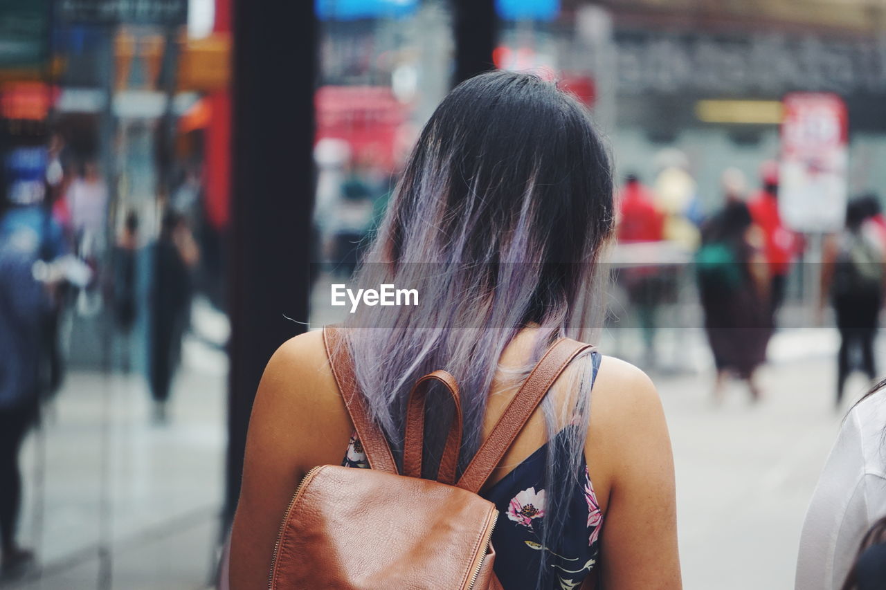 REAR VIEW PORTRAIT OF WOMAN STANDING ON STREET