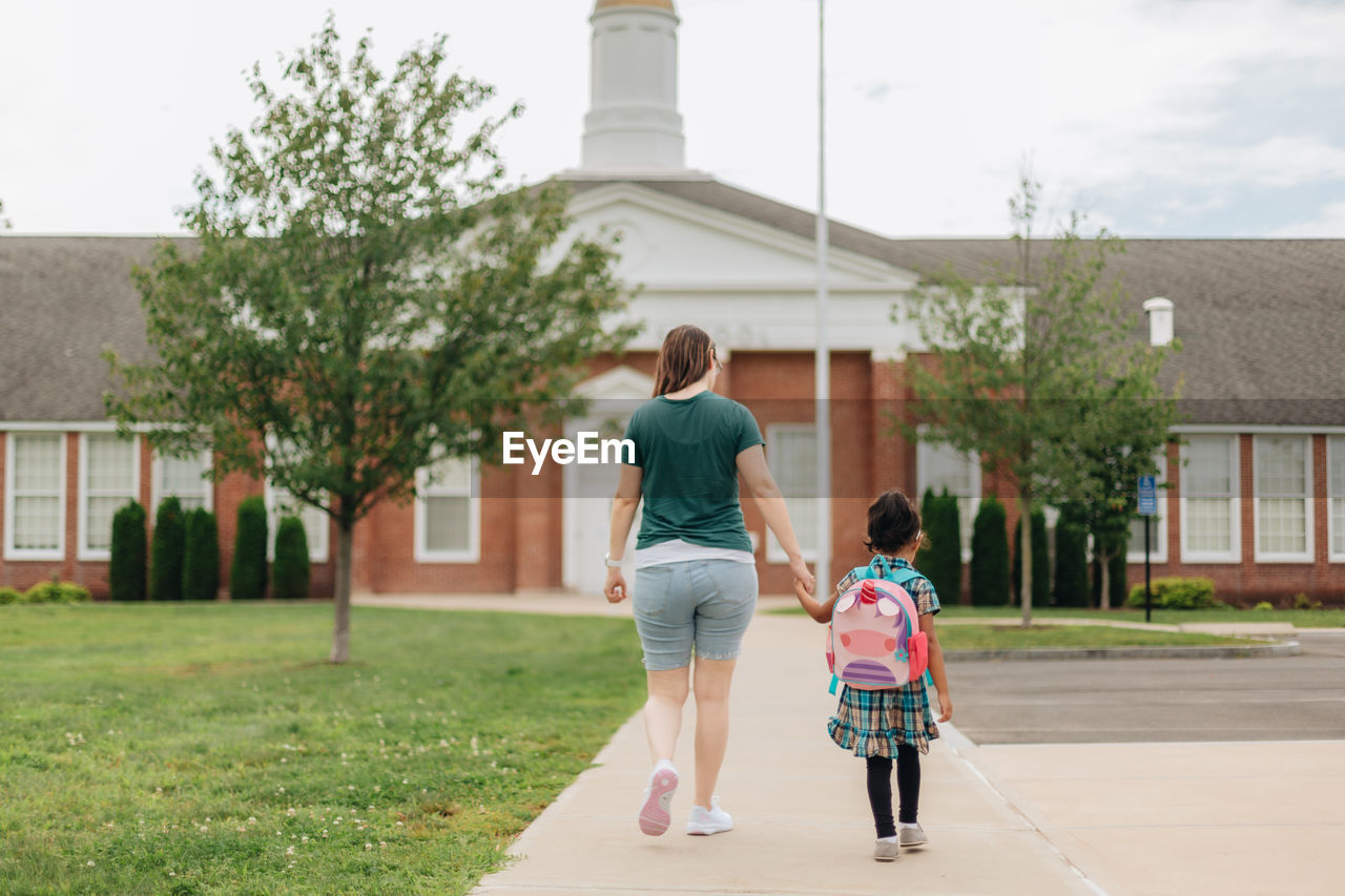 Young millennial mother sending daughter off back to school