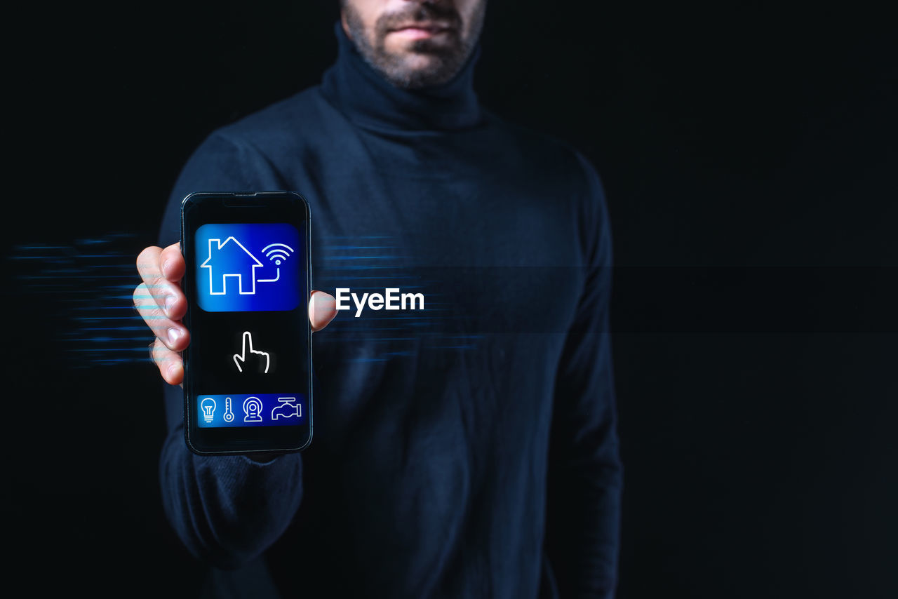black background, technology, one person, communication, adult, studio shot, wireless technology, indoors, men, internet, digital display, screen, computer, front view, portrait, dark, computer network, standing, touch screen, t-shirt, hood, copy space