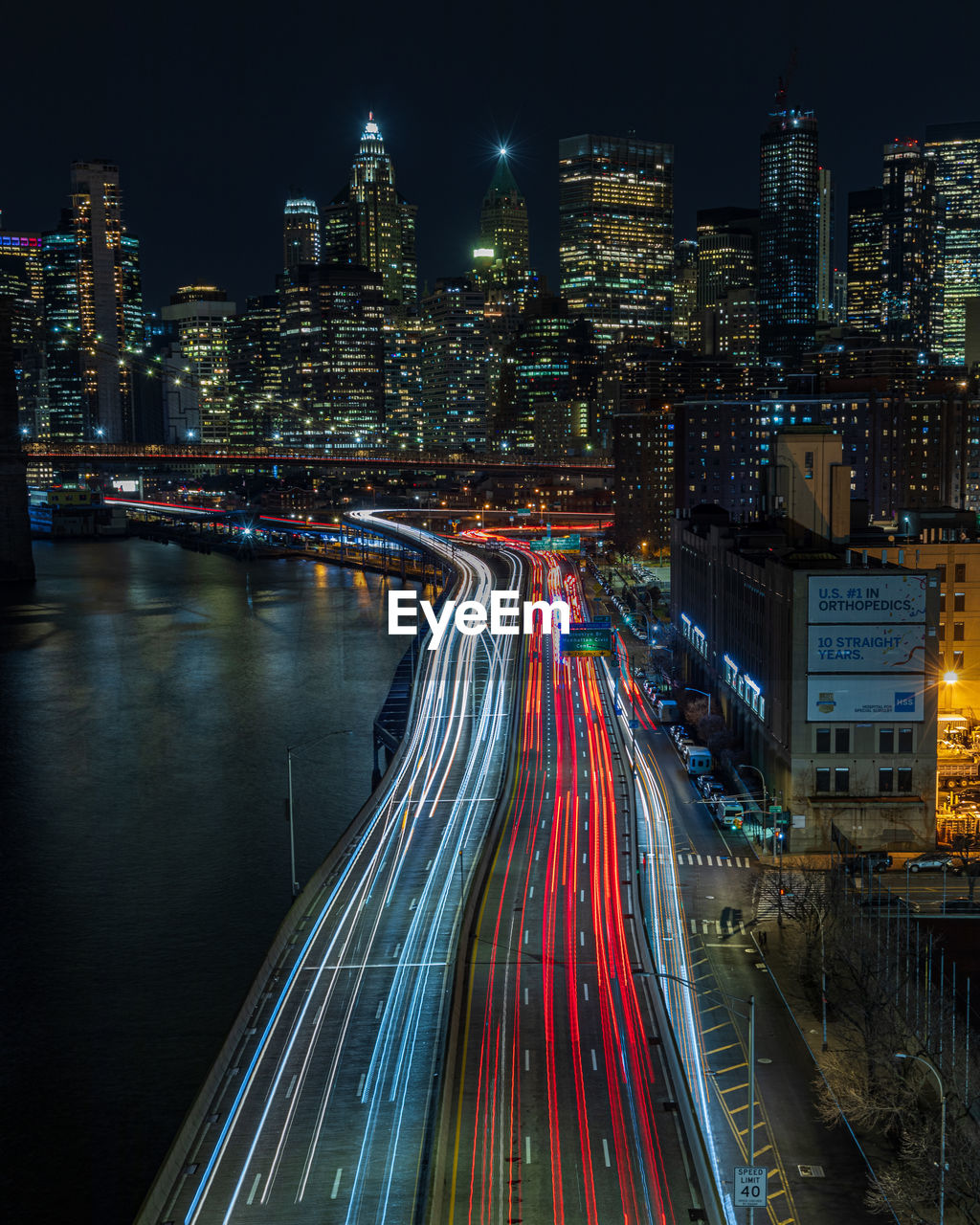 High angle view of light trails on road against buildings in city at night