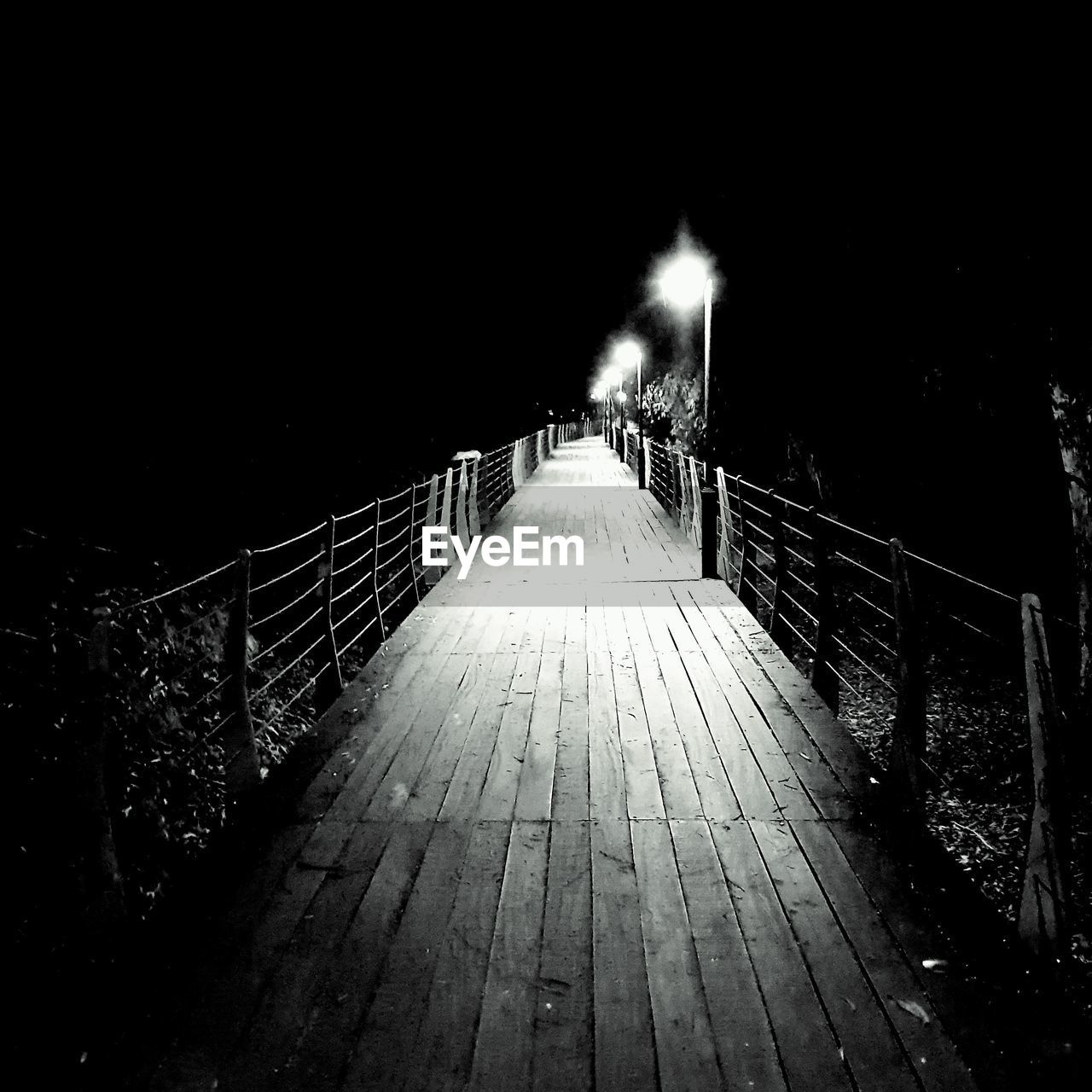 Illuminated footbridge against clear sky at night