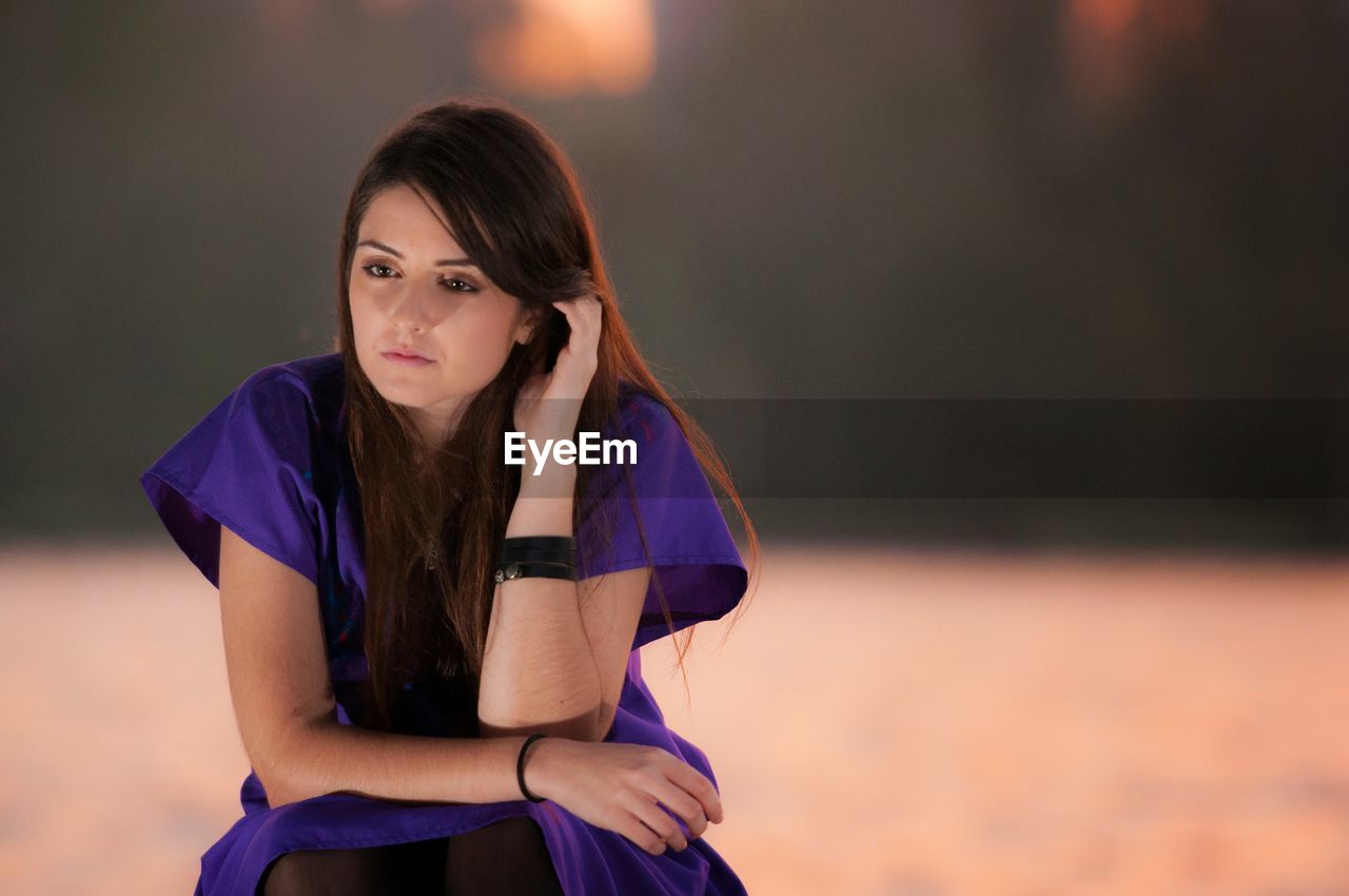 Thoughtful young woman sitting by lake