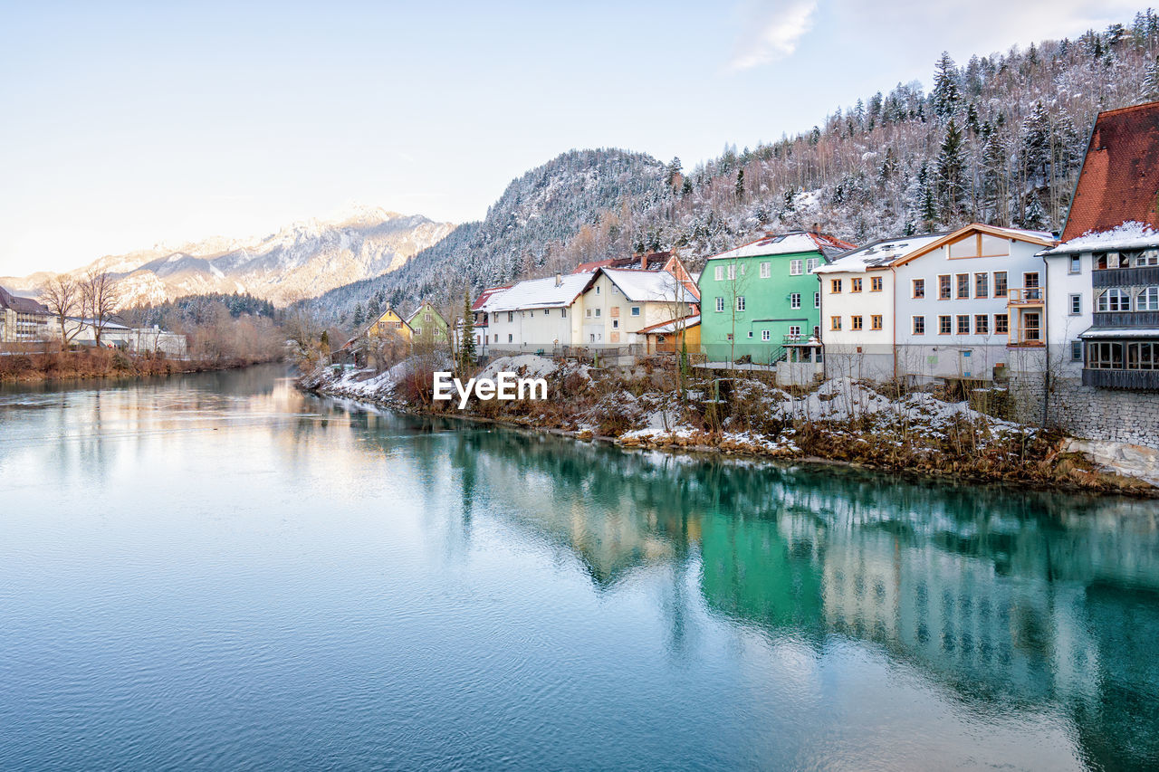 HOUSES BY LAKE AGAINST MOUNTAIN RANGE