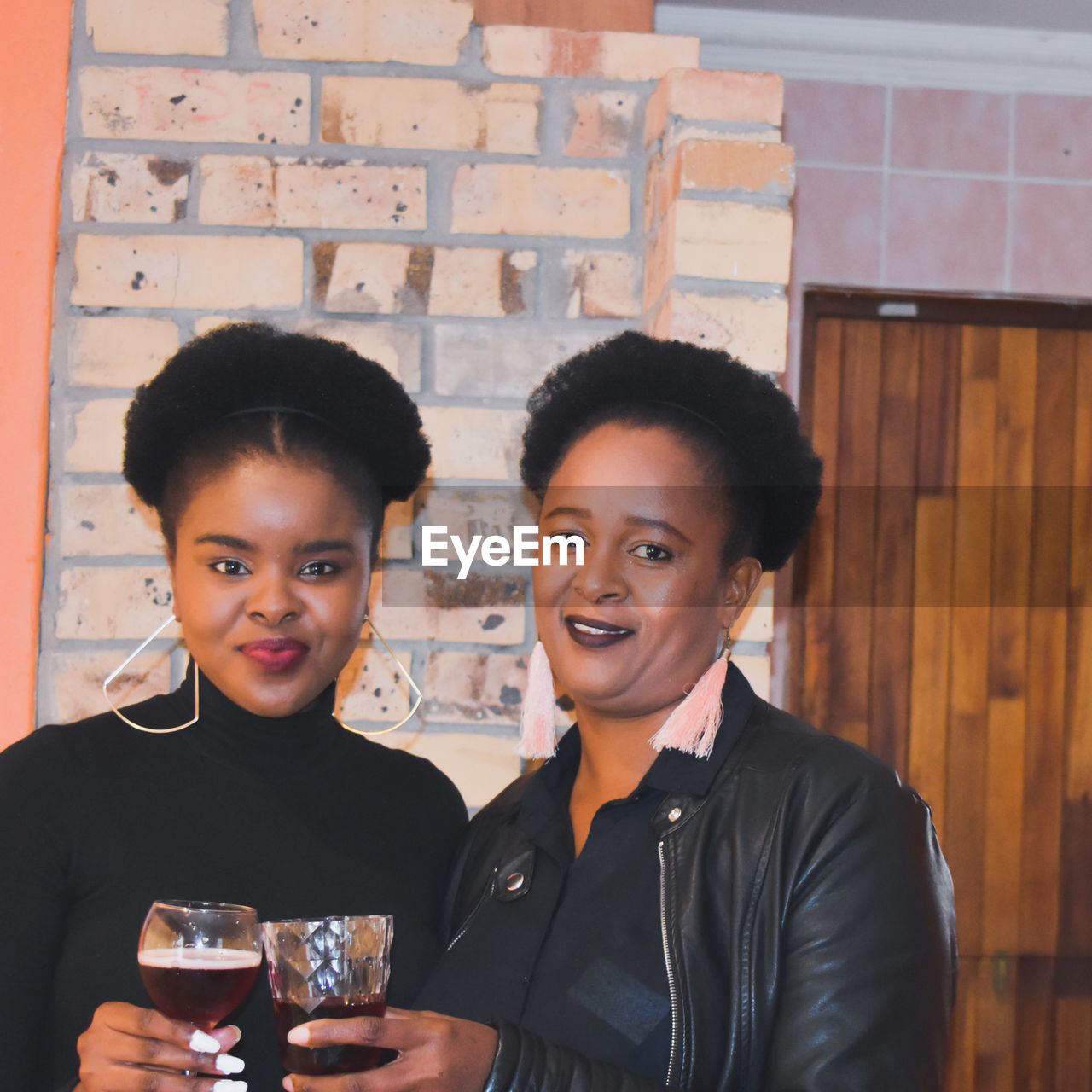 Portrait of mother and daughter toasting wines at home