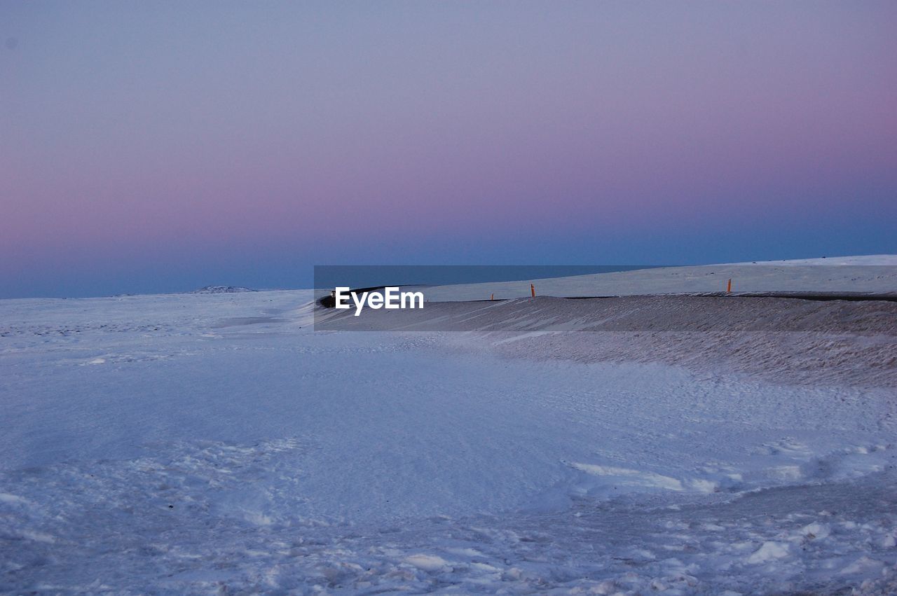 Scenic view of  icelandic  snow fields and road against  pink sky during winter