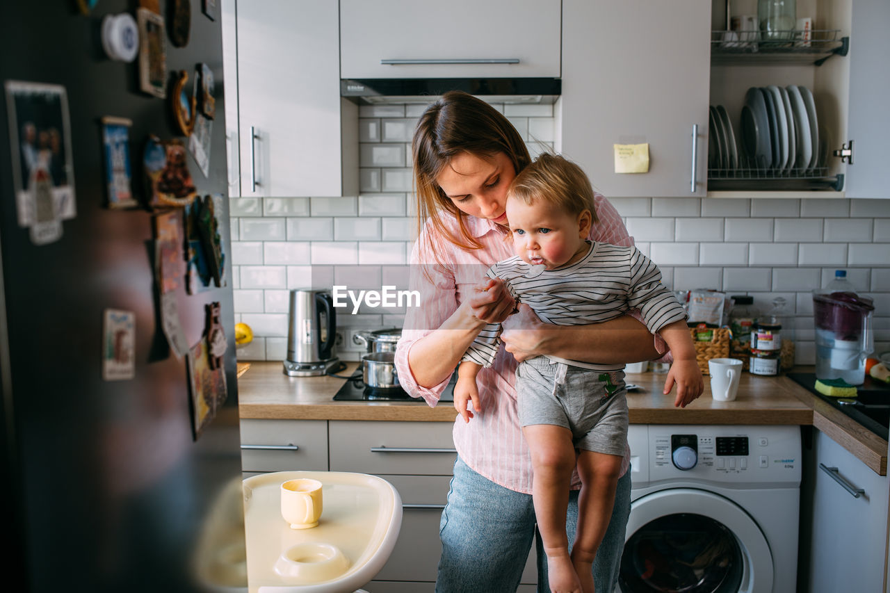 Mom feeds a small child at home with yogurt from a spoon. family concept