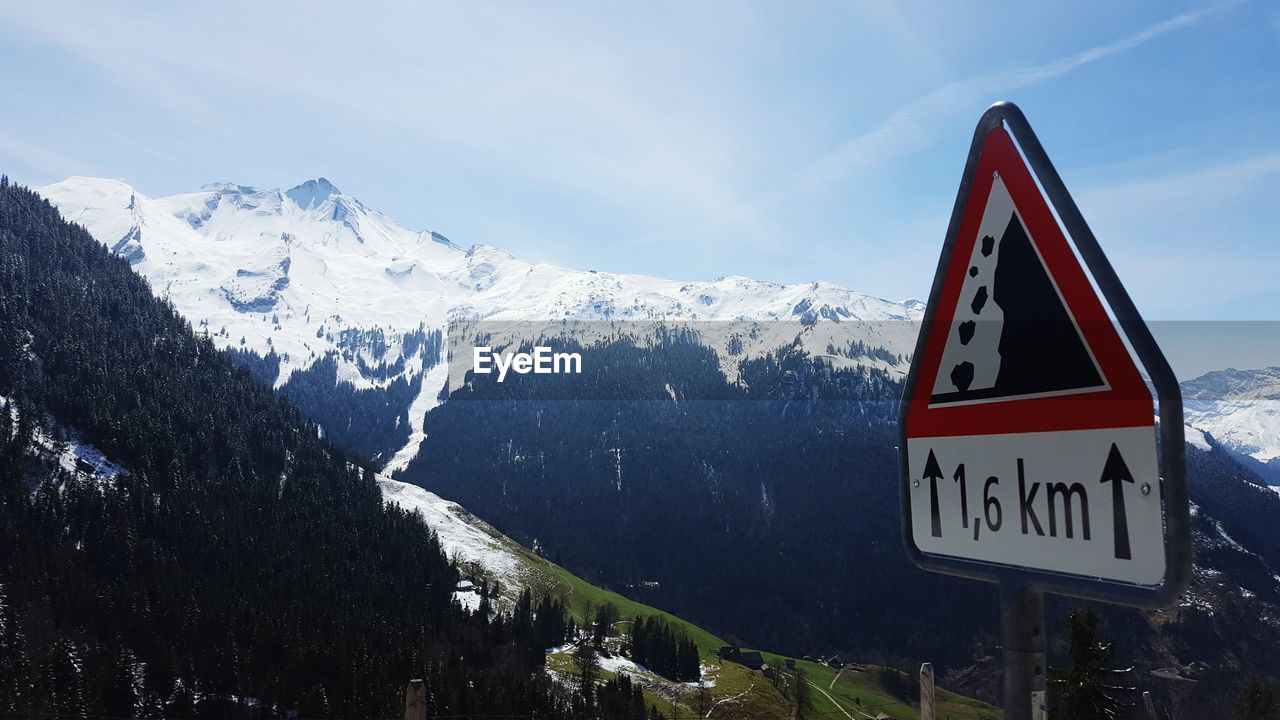 Sign board on mountains against sky