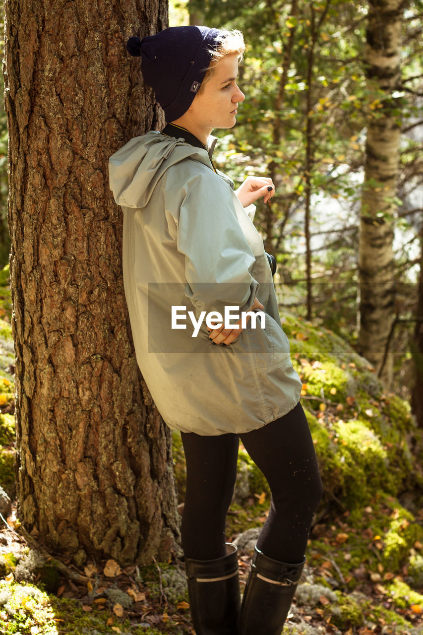 Female tourist leaning on tree in wood scenic photography