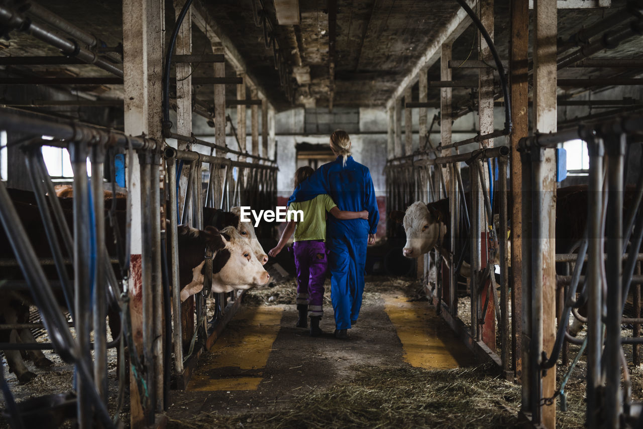 Woman walking with girl in barn
