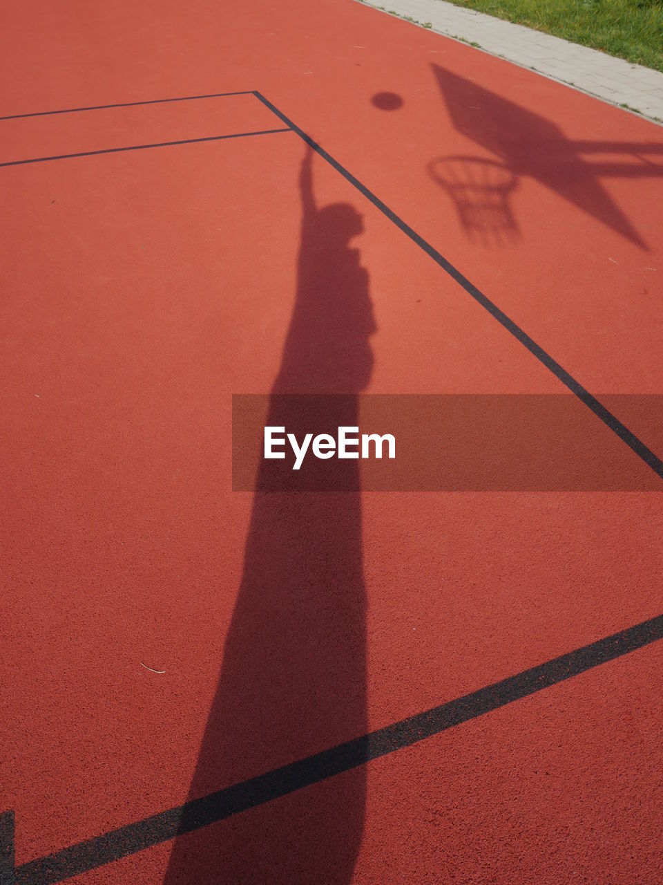 Shadow of man playing basketball on court