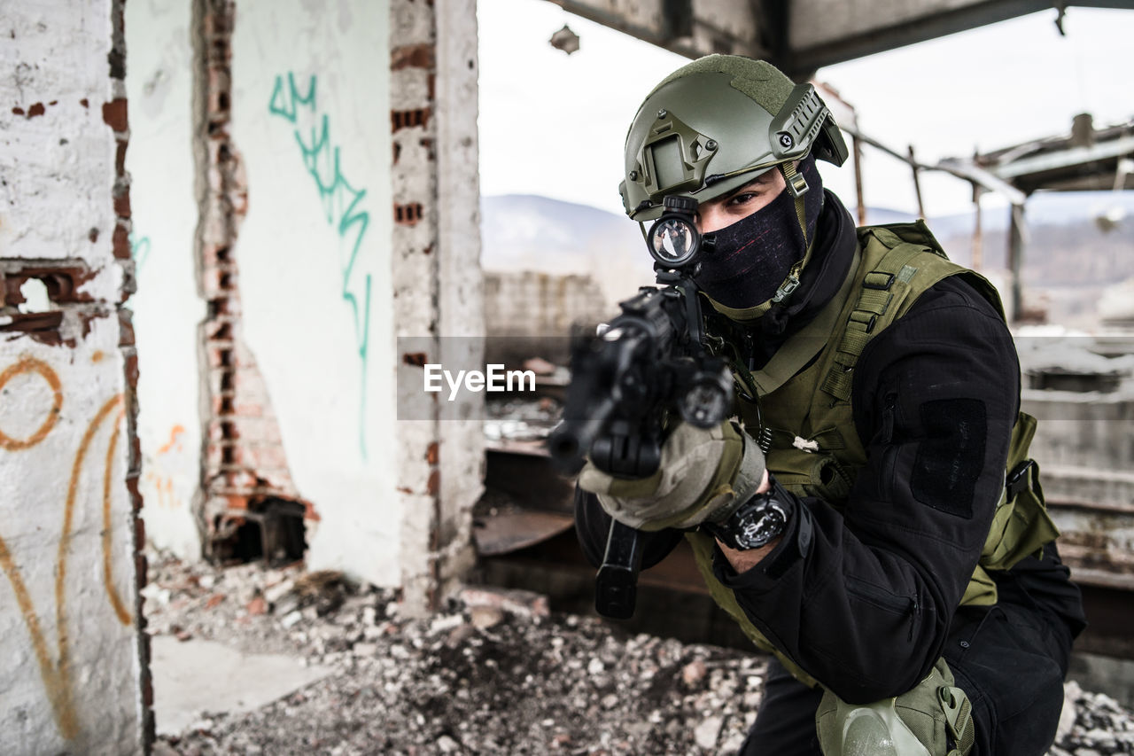 Portrait of army soldier aiming rifle while in building