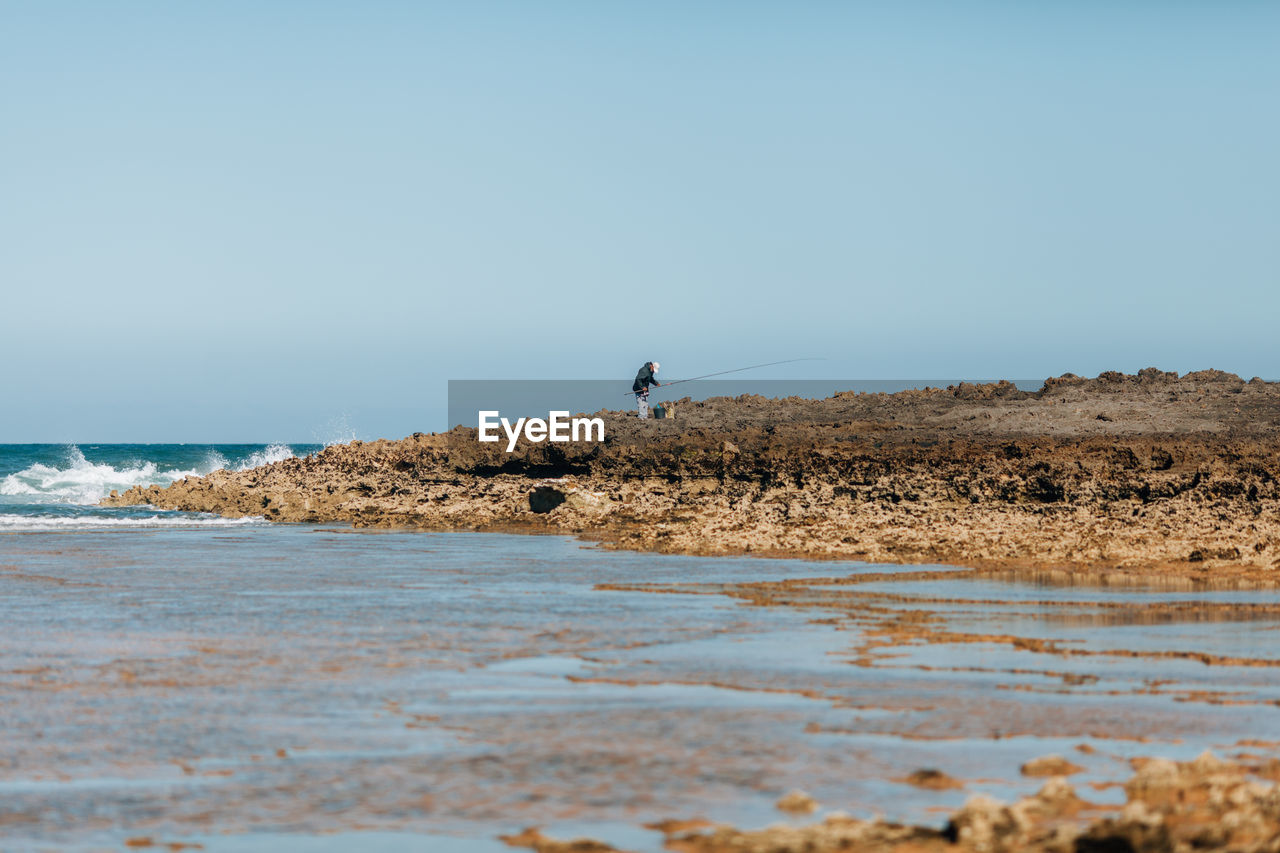 Man on beach against clear sky