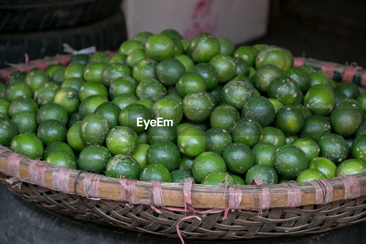 Close-up of limes in basket for sale at market stall