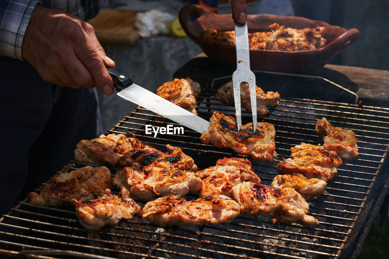 Midsection of man preparing food on barbecue grill