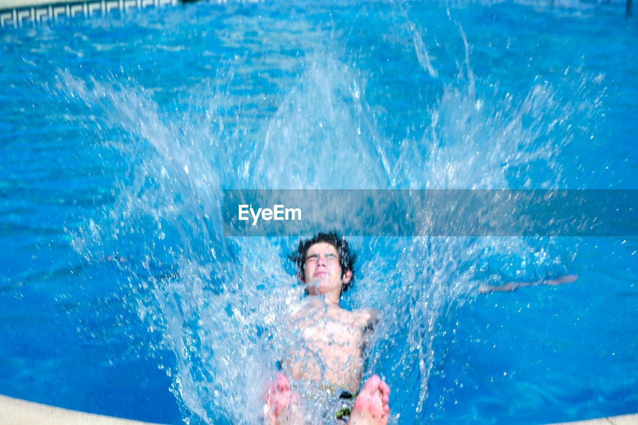 High angle view of shirtless teenage boy diving in swimming pool