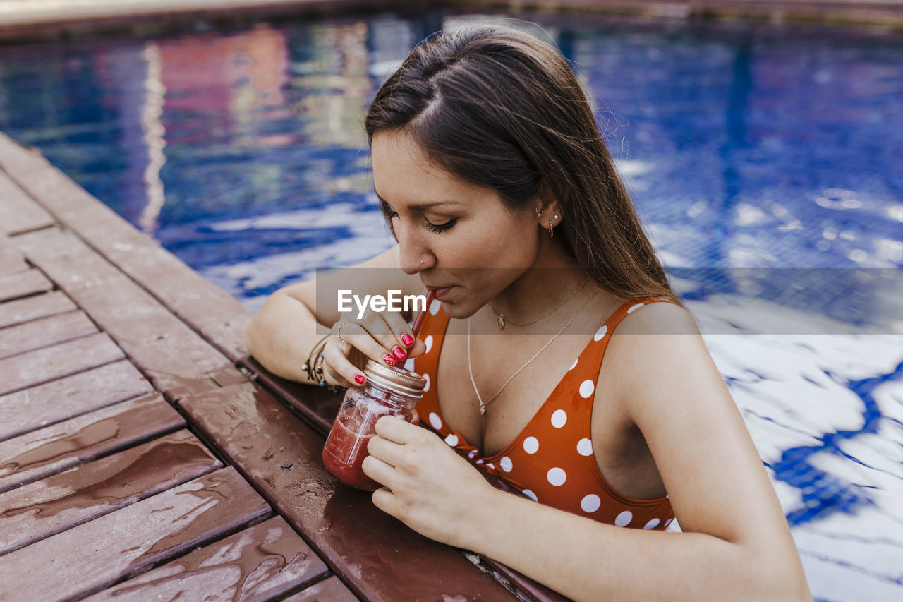 YOUNG WOMAN LOOKING AWAY WHILE SITTING ON LEAF