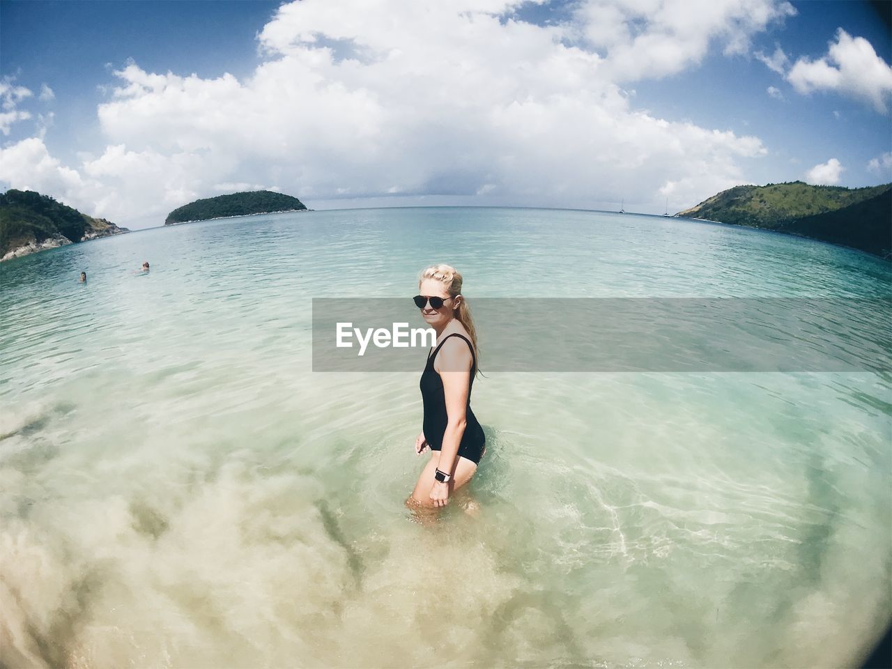 Side view of seductive woman standing in sea against sky