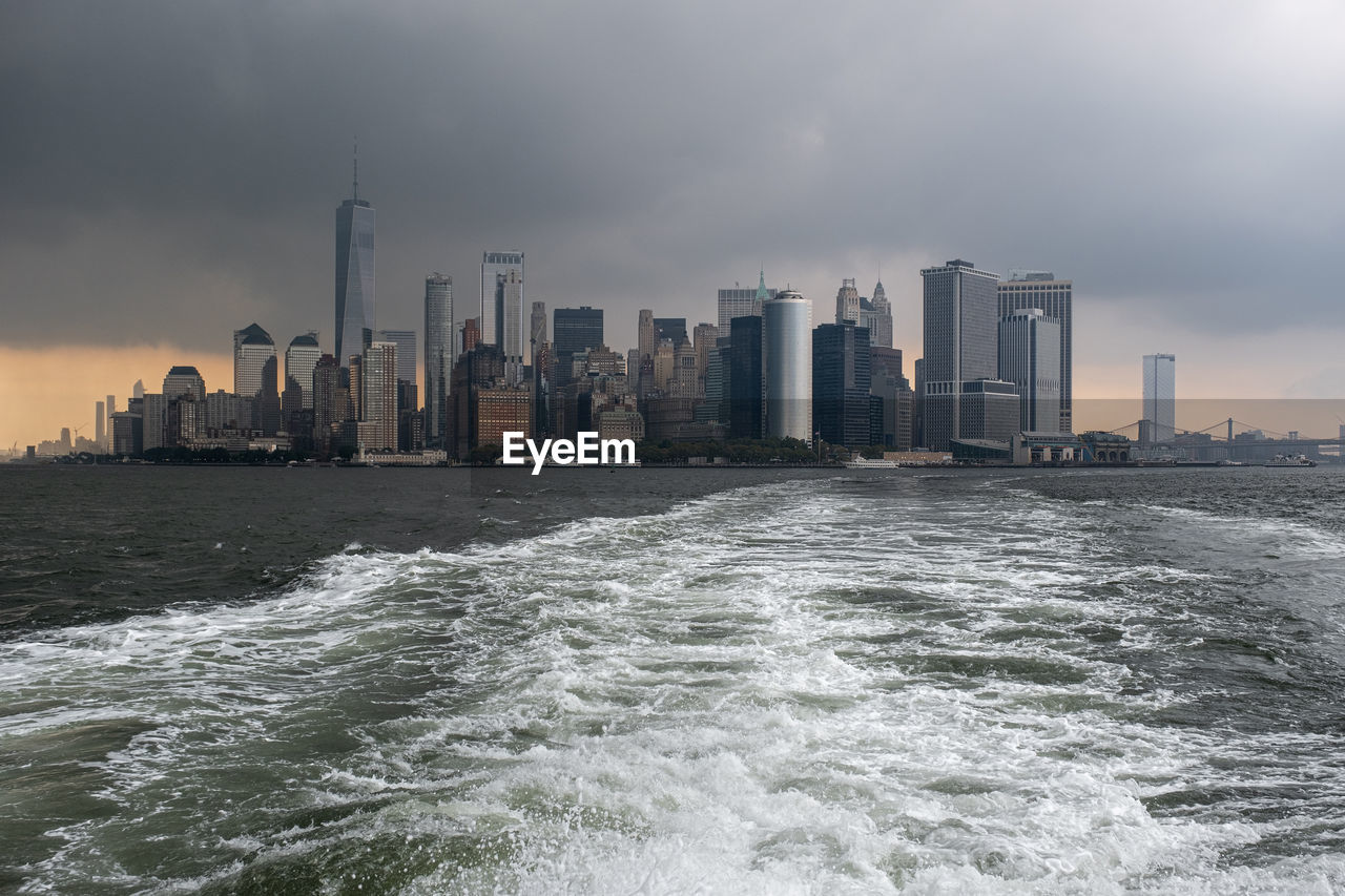 SEA BY BUILDINGS AGAINST SKY IN CITY