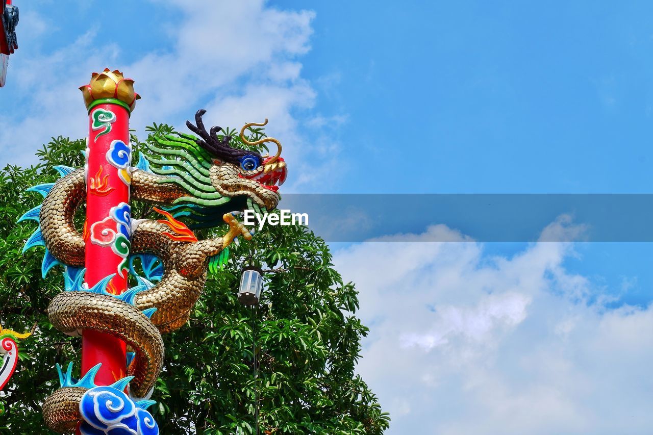 Low angle view of chinese dragon statue against blue sky