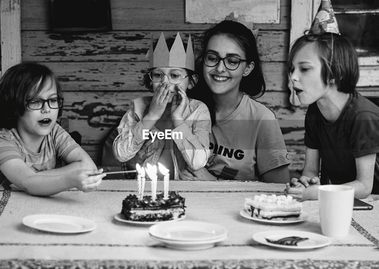 Smiling friends celebrating birthday on table at home