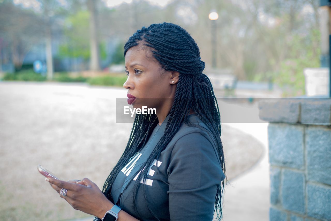 Thoughtful woman using mobile phone in city