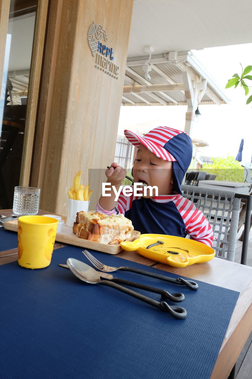 Cute girl eating while sitting at restaurant