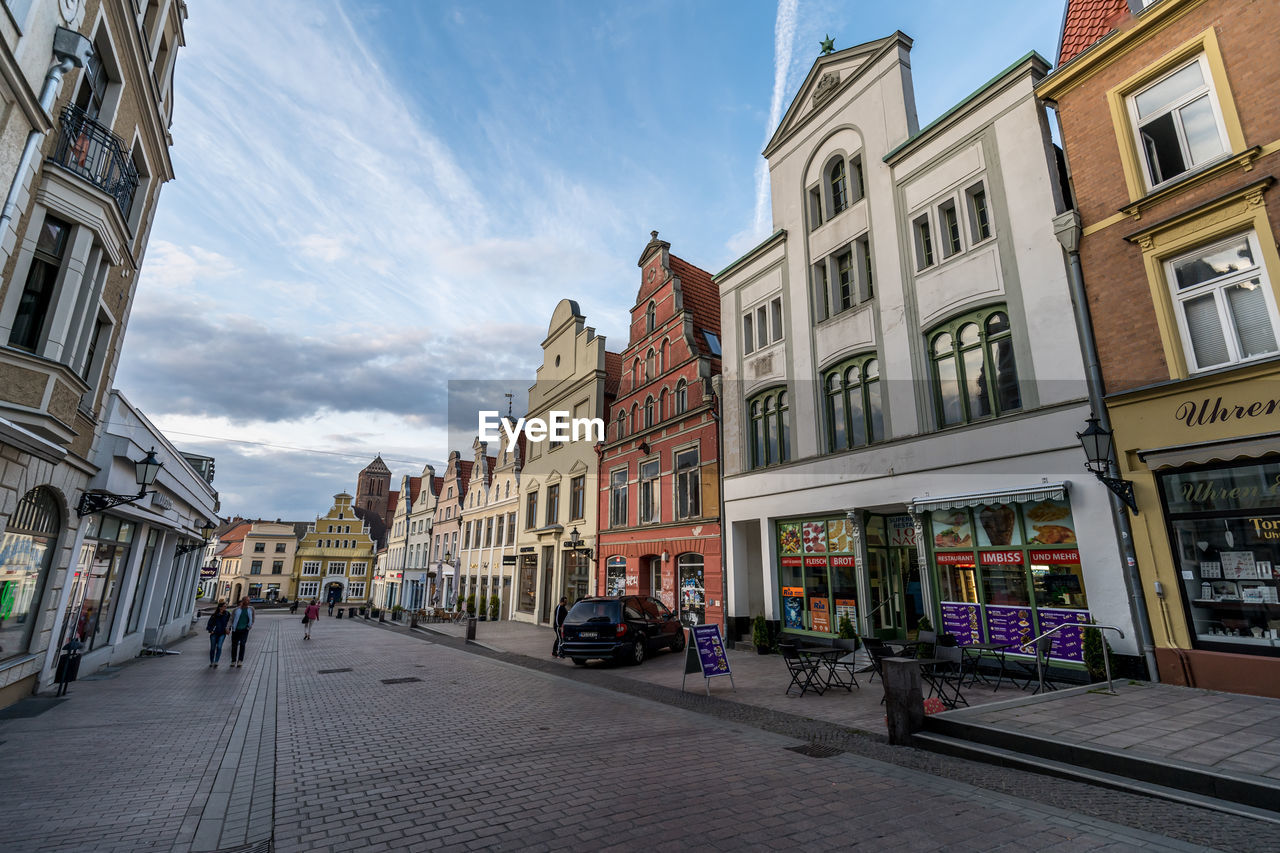 STREET BY BUILDINGS AGAINST SKY