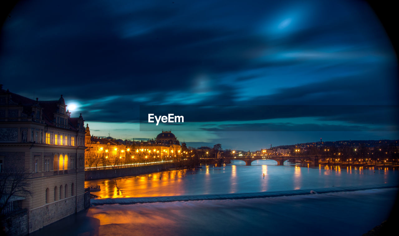 Illuminated buildings by river at night