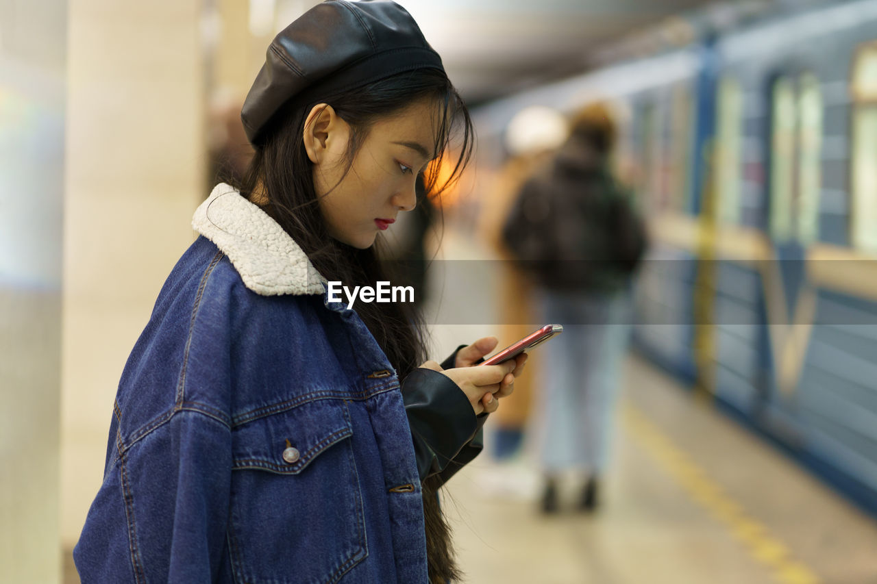 Addicted from phone chinese girl pay no attention on arriving train on platform scroll social media