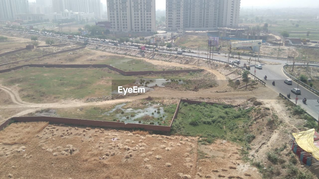 HIGH ANGLE VIEW OF CARS ON CITY IN BACKGROUND