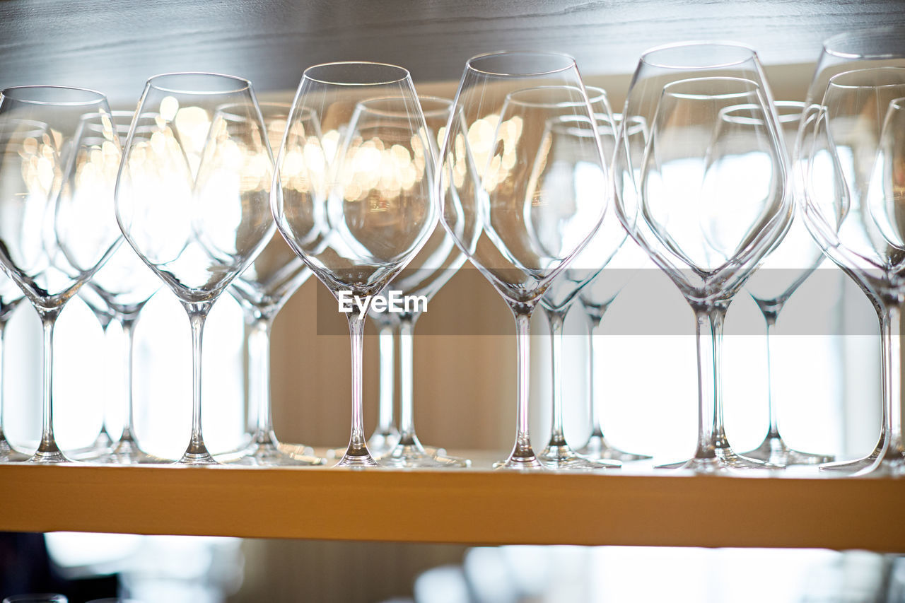 CLOSE-UP OF WINE GLASS ON TABLE AGAINST THE WALL