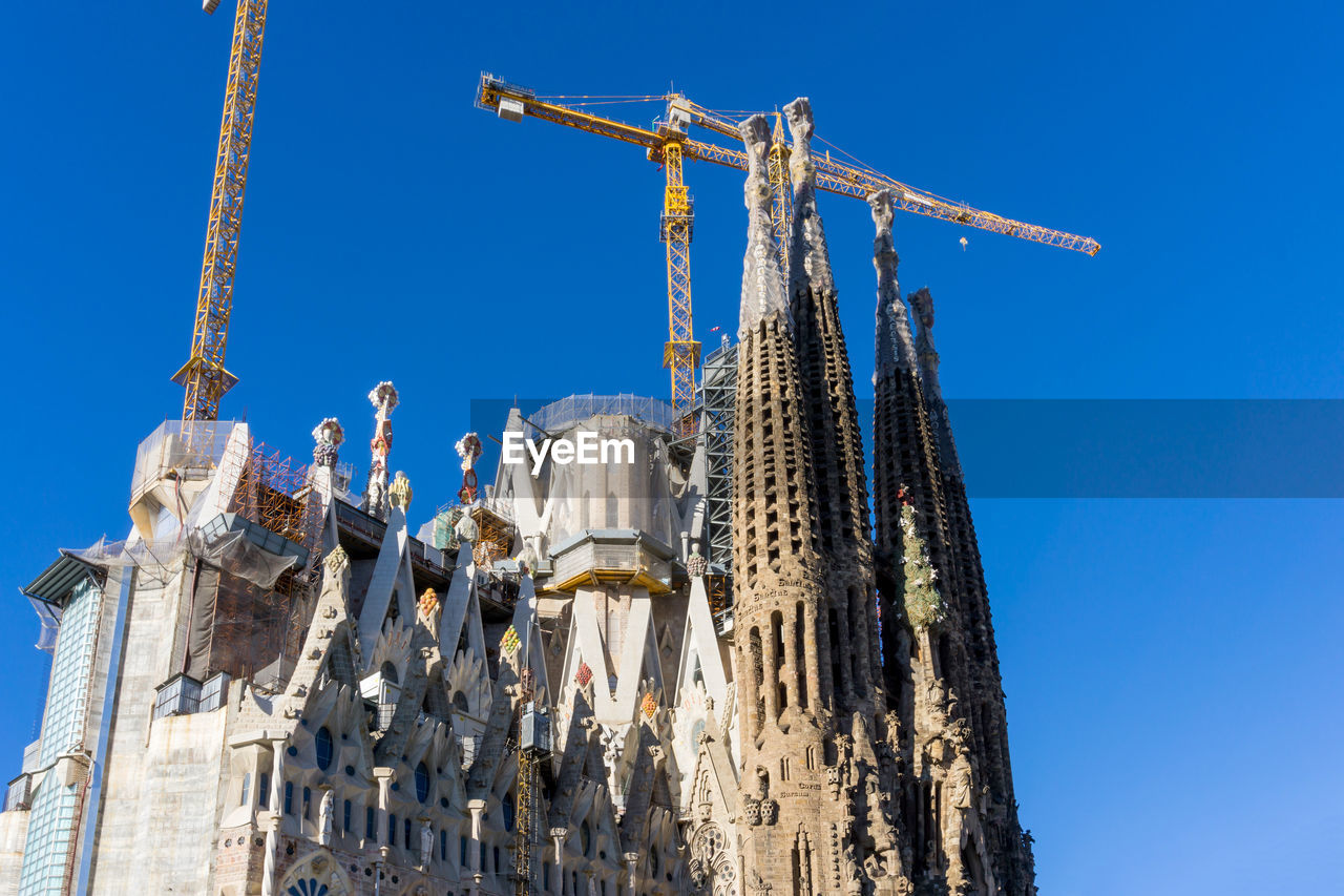 Low angle view of incomplete sagrada familia against clear blue sky